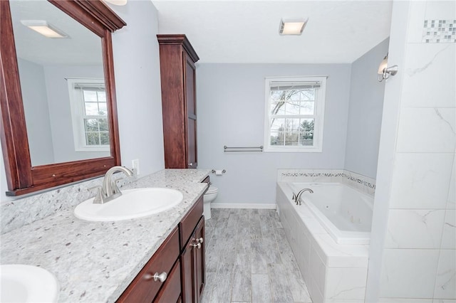 full bath featuring toilet, plenty of natural light, vanity, and a tub with jets