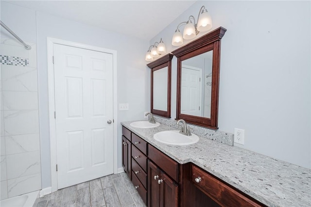 bathroom with double vanity, a sink, wood finish floors, and walk in shower