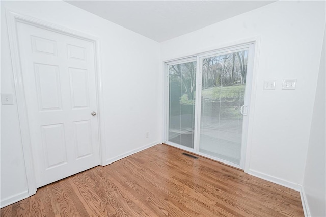 empty room featuring light wood-style flooring, baseboards, and visible vents