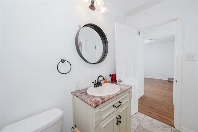 bathroom featuring toilet, vanity, and visible vents