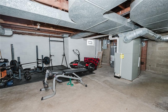 workout room featuring gas water heater, heating unit, electric panel, and concrete block wall