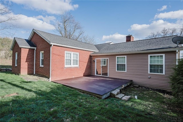 rear view of property featuring brick siding, a yard, a deck, and a chimney