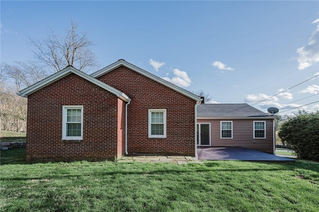 rear view of property with a patio, brick siding, and a lawn