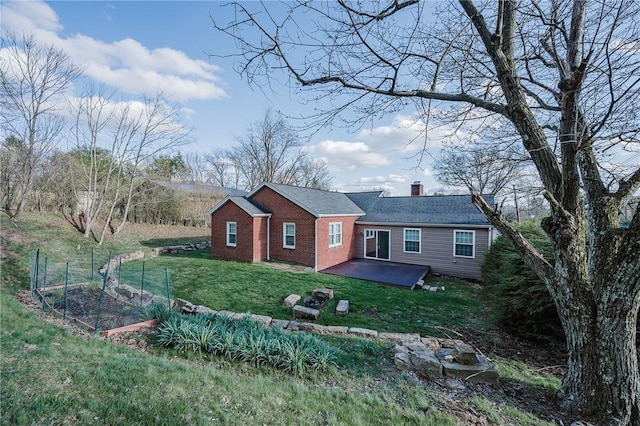 view of front of house featuring a patio, brick siding, a chimney, and a front yard