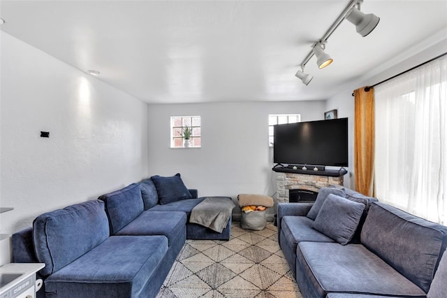 living room featuring track lighting and a stone fireplace