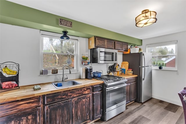 kitchen featuring butcher block counters, a healthy amount of sunlight, a sink, and appliances with stainless steel finishes