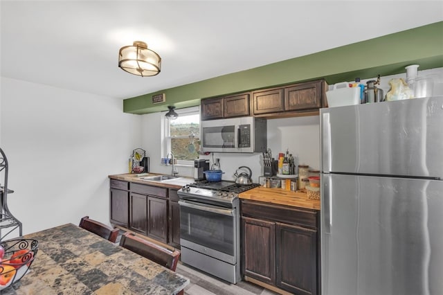 kitchen with appliances with stainless steel finishes, a sink, and dark brown cabinets