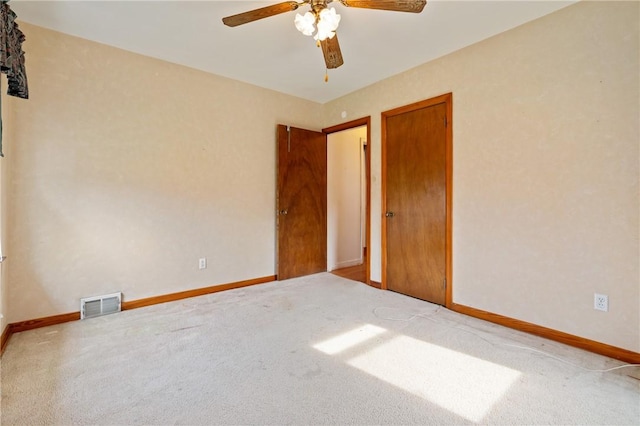carpeted spare room featuring visible vents, baseboards, and a ceiling fan