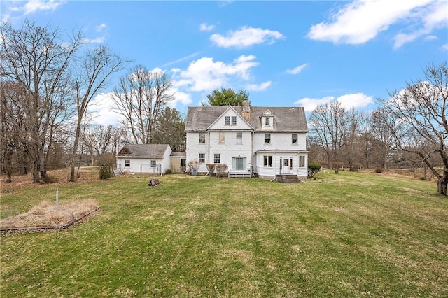 rear view of house with a yard, an outdoor structure, and a chimney