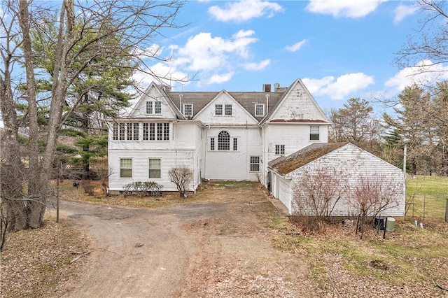 view of front of house featuring dirt driveway, fence, and a garage