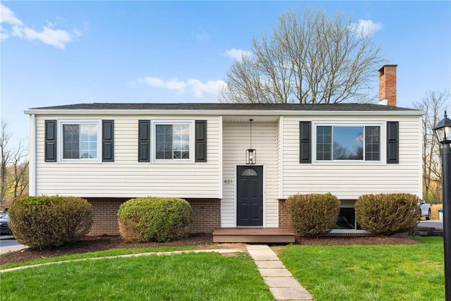 bi-level home featuring a front yard, brick siding, and a chimney