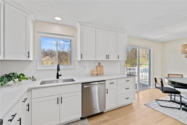 kitchen with a sink, light countertops, stainless steel dishwasher, and white cabinetry