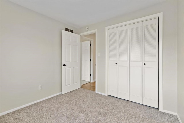 unfurnished bedroom with a closet, carpet flooring, visible vents, and baseboards