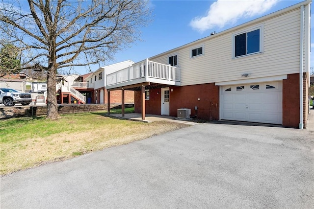 view of front of property featuring a front yard, central air condition unit, a garage, stairs, and driveway