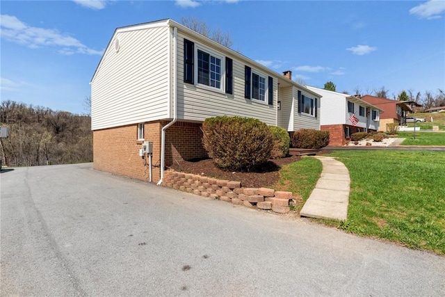 view of home's exterior featuring a yard, brick siding, and a chimney