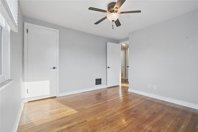unfurnished bedroom featuring visible vents, hardwood / wood-style flooring, baseboards, and ceiling fan