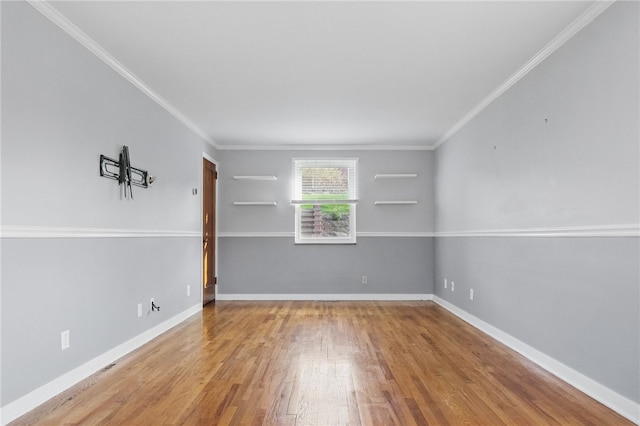 spare room featuring crown molding, baseboards, and wood finished floors