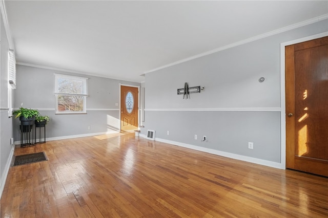 unfurnished living room with crown molding, visible vents, baseboards, and wood-type flooring