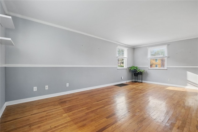 empty room with ornamental molding, baseboards, and hardwood / wood-style flooring