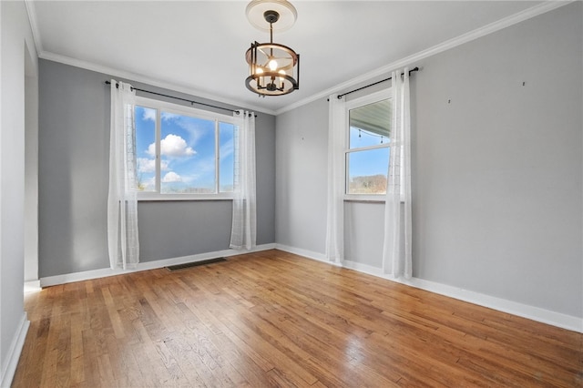 empty room with crown molding, baseboards, a notable chandelier, and hardwood / wood-style flooring