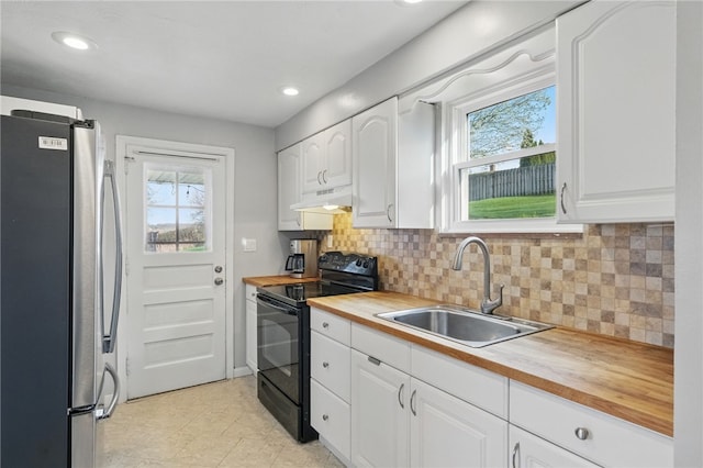 kitchen featuring freestanding refrigerator, under cabinet range hood, a sink, black range with electric stovetop, and wooden counters