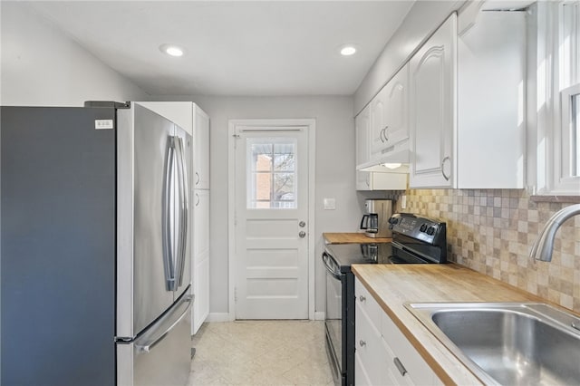 kitchen featuring white cabinets, a sink, freestanding refrigerator, under cabinet range hood, and black / electric stove
