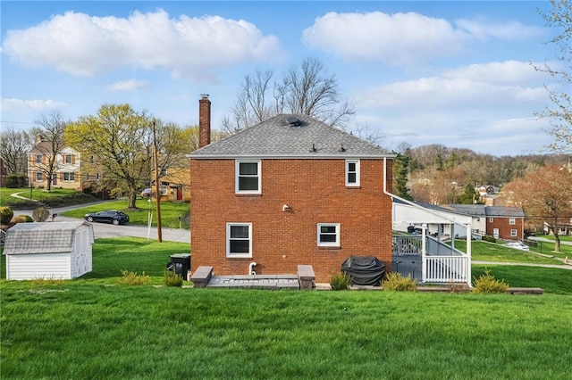 back of property featuring brick siding, a yard, a shed, and a chimney