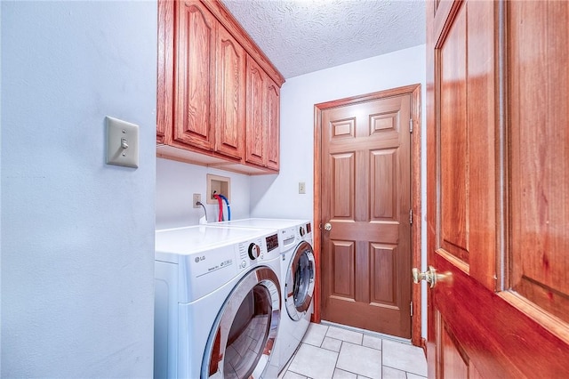 washroom featuring light tile patterned floors, washer and clothes dryer, a textured ceiling, and cabinet space
