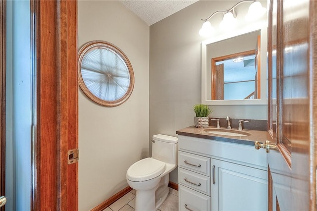 bathroom with vanity, baseboards, tile patterned flooring, a textured ceiling, and toilet