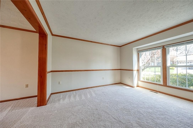 carpeted empty room with a textured ceiling, baseboards, ornamental molding, and visible vents