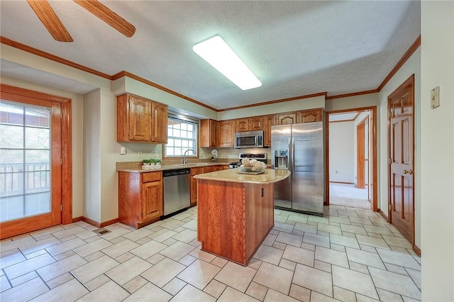 kitchen featuring a center island, light countertops, brown cabinetry, appliances with stainless steel finishes, and a sink