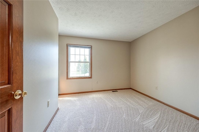unfurnished room featuring light carpet, baseboards, visible vents, and a textured ceiling