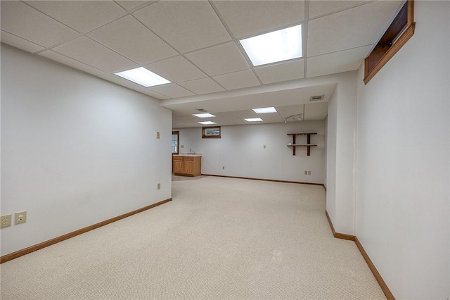 basement featuring visible vents, baseboards, a paneled ceiling, and light carpet