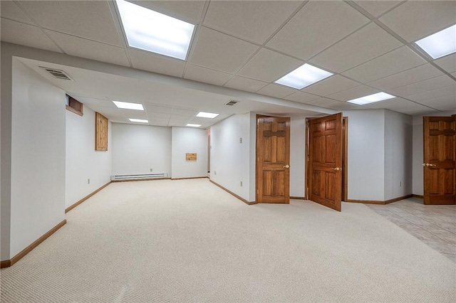 finished below grade area with light carpet, a baseboard heating unit, baseboards, and visible vents