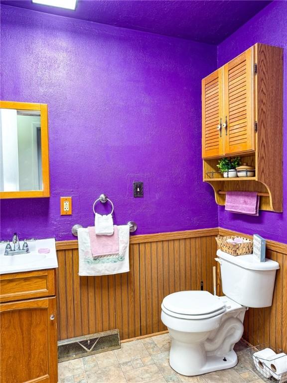 210 Locust St, Rural Valley Boro, PA 16249 - half bathroom with wooden walls, visible vents, toilet, and wainscoting