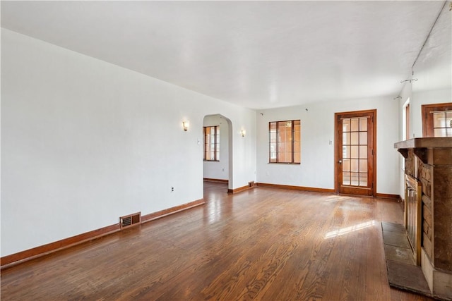 210 Morewood Rd, Shaler, PA 15116 - unfurnished living room with a stone fireplace, visible vents, baseboards, arched walkways, and wood finished floors