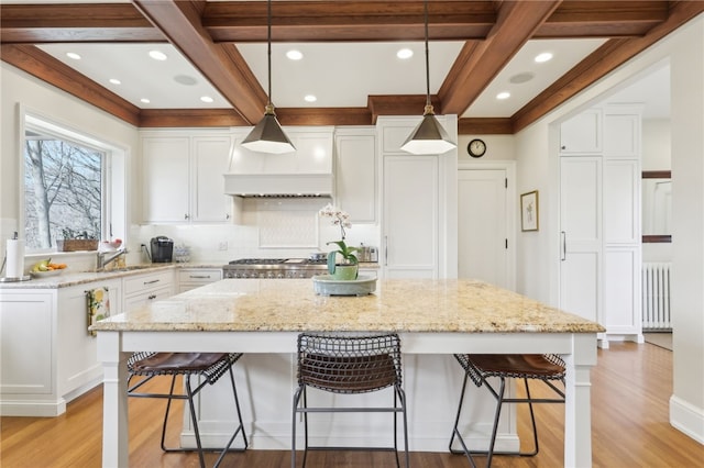 918 W Waldheim Rd, Fox Chapel, PA 15215 - kitchen featuring radiator heating unit, light wood-style flooring, white cabinetry, beamed ceiling, and a kitchen island