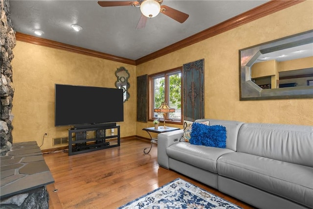 living area featuring visible vents, ornamental molding, ceiling fan, a textured wall, and wood finished floors