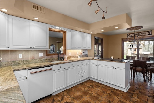 kitchen featuring recessed lighting, a peninsula, visible vents, white dishwasher, and a sink