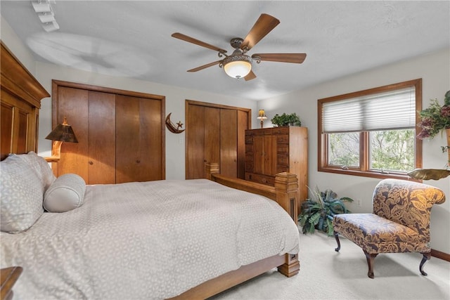 bedroom featuring carpet, baseboards, multiple closets, and ceiling fan