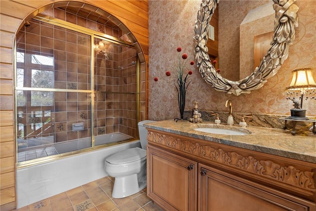 bathroom featuring shower / bath combination with glass door, vanity, wallpapered walls, tile patterned flooring, and toilet