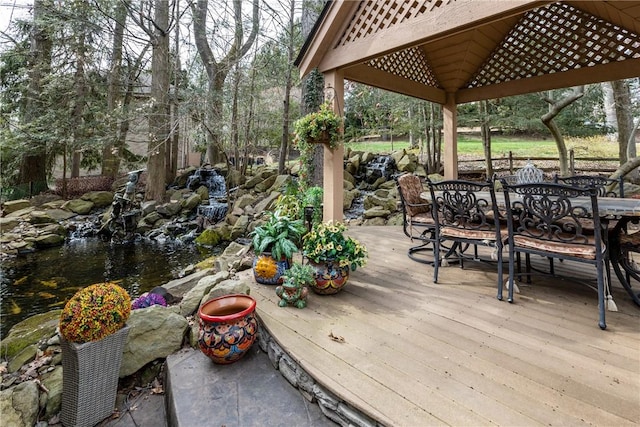 deck with a garden pond, outdoor dining space, and a gazebo