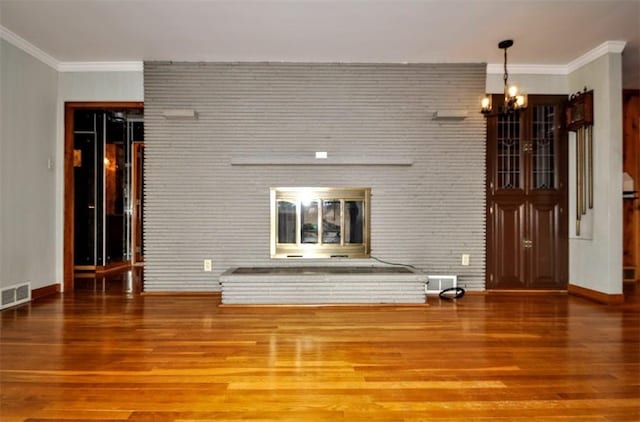 unfurnished living room featuring a fireplace, visible vents, an inviting chandelier, and wood finished floors