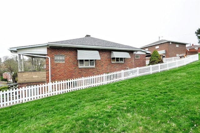 exterior space with a shingled roof, brick siding, fence, and a lawn