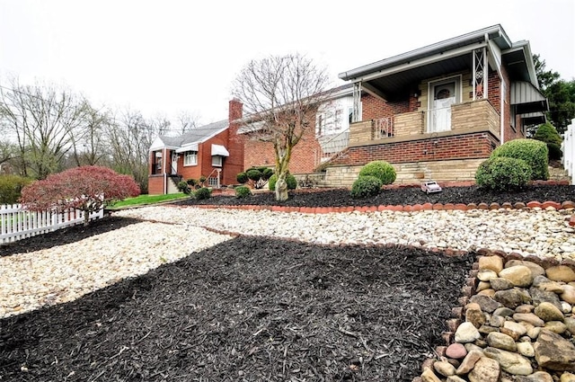 view of side of property featuring brick siding, fence, and a chimney