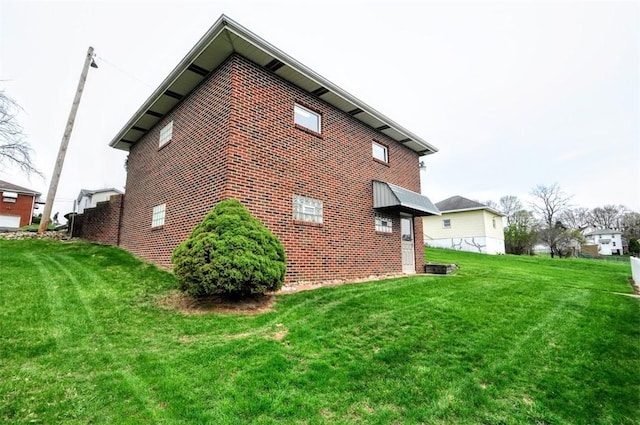 view of property exterior with brick siding and a lawn
