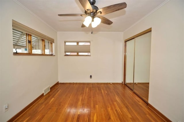 unfurnished bedroom with crown molding, wood finished floors, and multiple windows