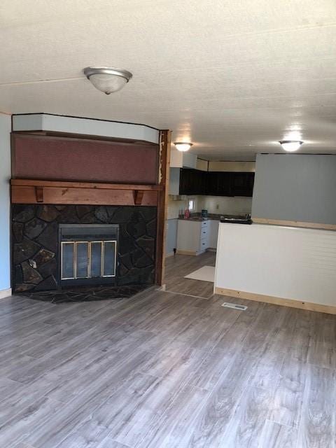 23 Gilmore Ln, Sandy Lake Twp, PA 16153 - unfurnished living room featuring baseboards, a stone fireplace, and light wood-style flooring