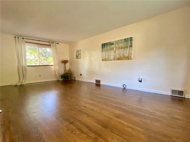 unfurnished room featuring wood finished floors, baseboards, and visible vents