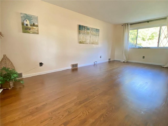empty room with visible vents, baseboards, and wood finished floors